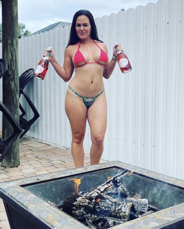 Christie model showcasing a sheer USA themed bikini by Oh Lola Swimwear while holding champagne bottles