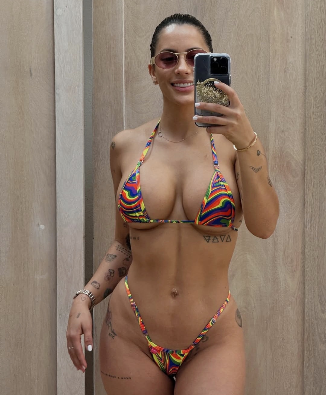 Female Model from Costa Rica posing in front of a mirror to showcase the frontal view of a gradient colors bikini