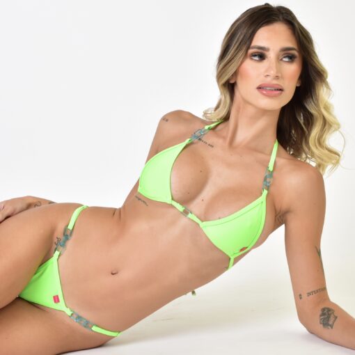 Model posing with a neon green bikini with chain accents for luxury beachwear